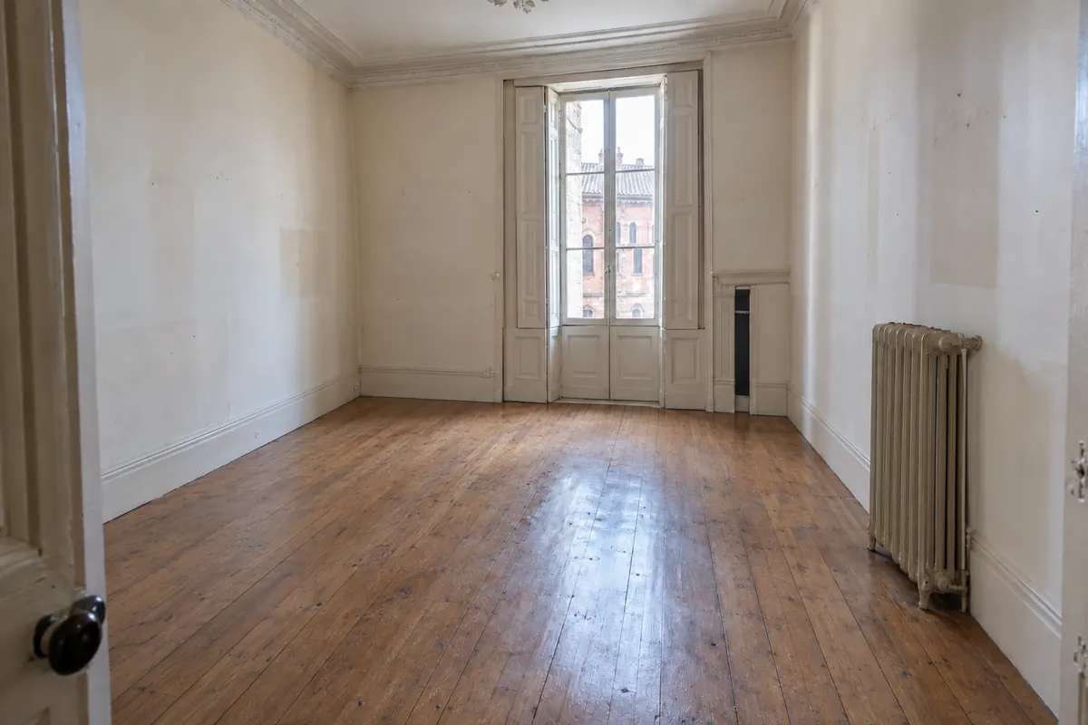 La même chambre vidée, parquet dégagé, après le débarras
