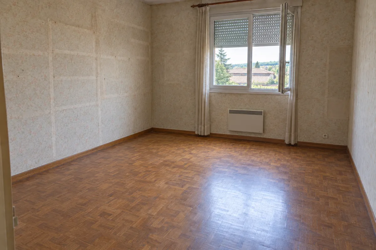 La même pièce entièrement vidée, parquet dégagé, après le débarras
