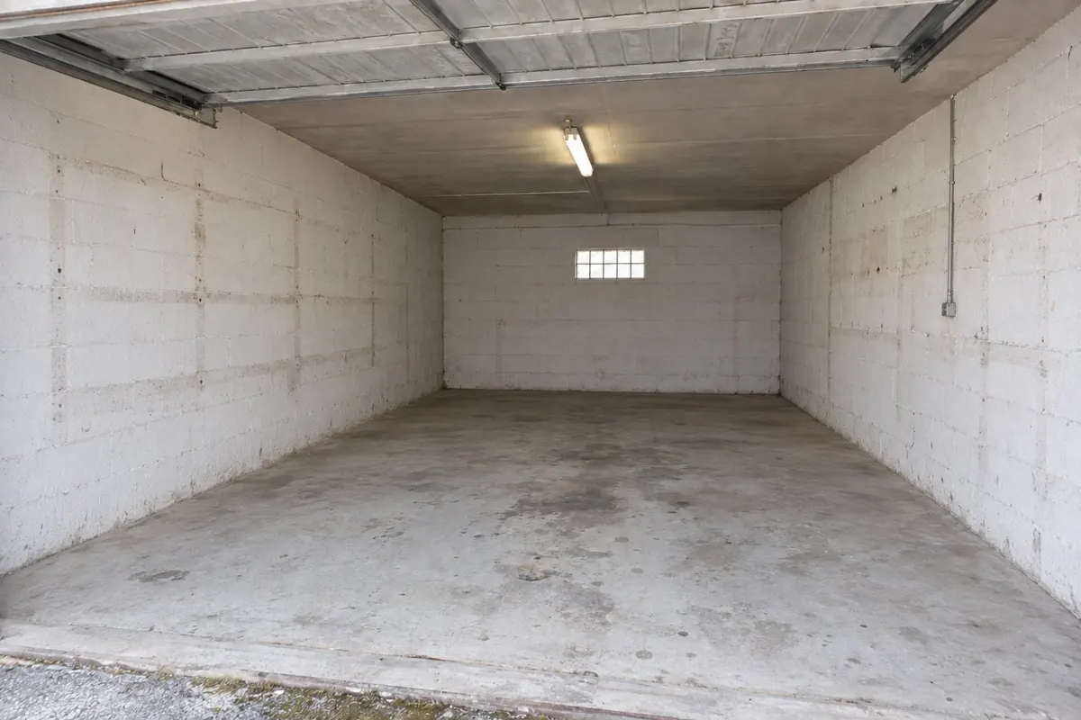 Le même garage entièrement vidé, sol en béton balayé, après le débarras