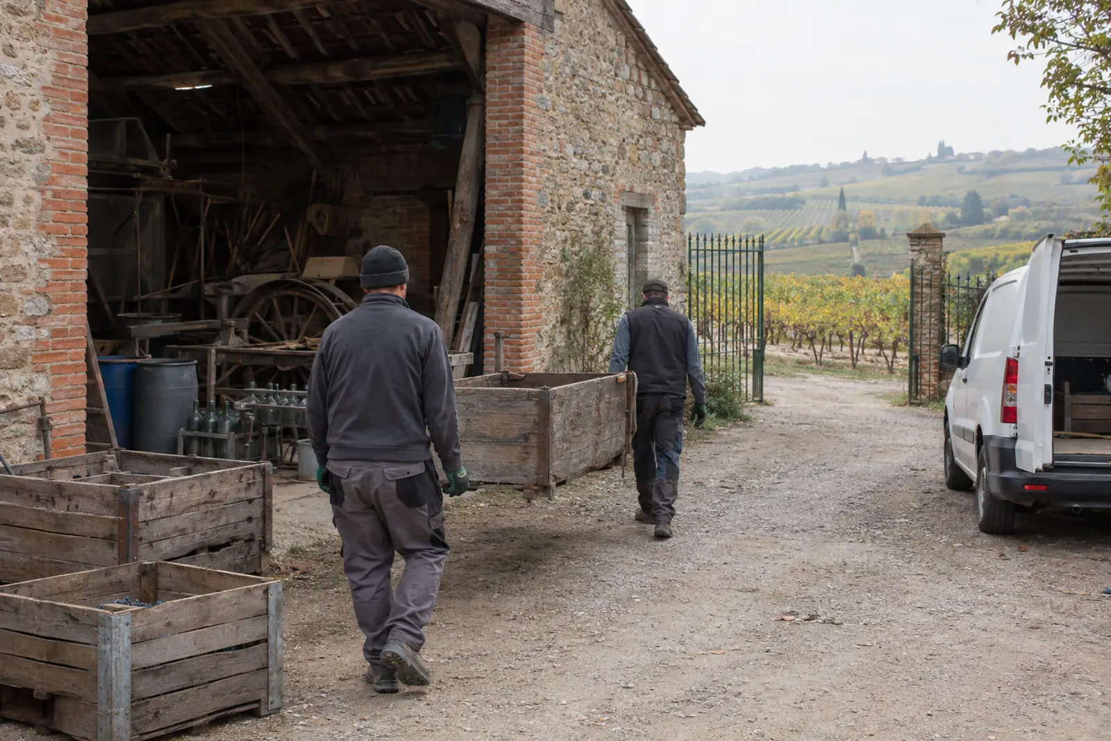Intervenants sortant des caisses de vendange d'une grange en brique et pierre, dans la cour d'une maison vigneronne du Gaillacois